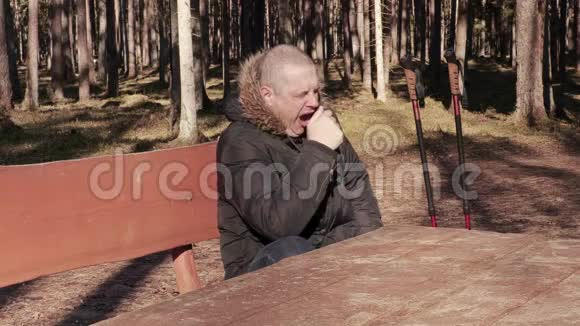公园里一个带着登山杖的疲惫的人在桌子旁打着哈欠视频的预览图
