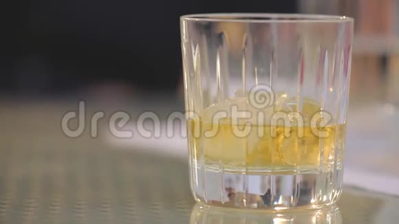 男人从桌子上拿出一杯加冰的威士忌把一杯加冰的威士忌放在桌子上特写视频的预览图