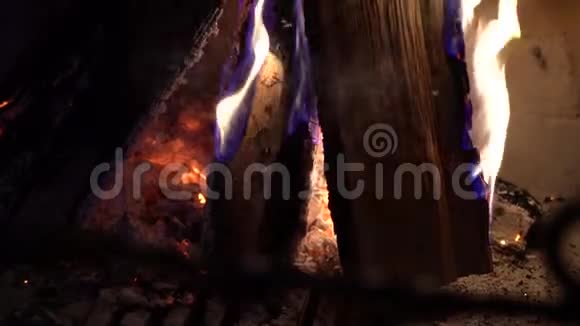 在黑暗中的传统砖壁炉中用燃烧的木头做特写视频的预览图