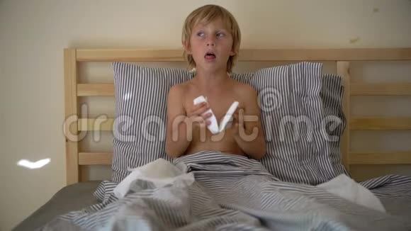一个生病的小男孩躺在床上的超慢镜头婴儿流感概念视频的预览图