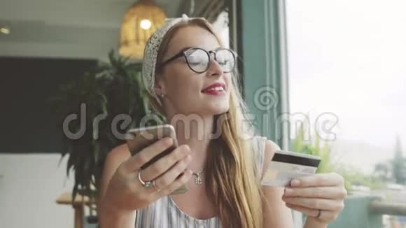 美女用信用卡和手机买新鞋女性在咖啡馆网上购物视频的预览图
