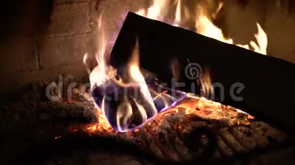在黑暗中的传统砖壁炉中用燃烧的木头做特写视频的预览图