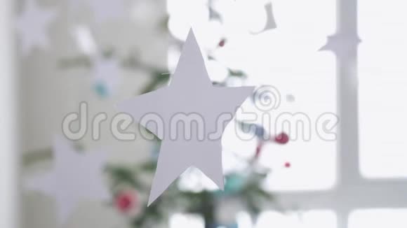 挂在窗户旁边一棵圣诞冷杉树前景的纸星星圣诞节的概念慢动作3840x2160视频的预览图