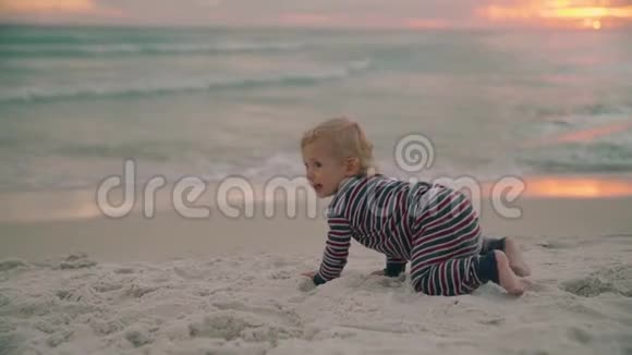 带着玩具在沙滩上爬行的小男孩视频的预览图