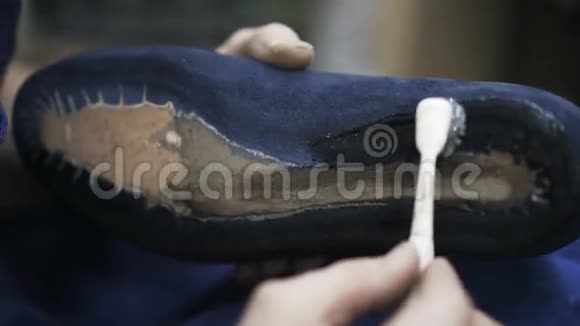 用刷子把胶水涂在蓝色鞋底上贴紧视频的预览图
