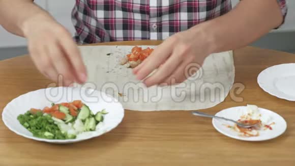 男人正在家里的餐桌上做饭皮塔蔬菜和葱配酱汁和蛋黄酱关闭视频的预览图