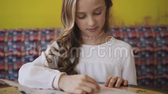 漂亮的微笑的年轻的女孩在咖啡馆里读菜单4K视频的预览图