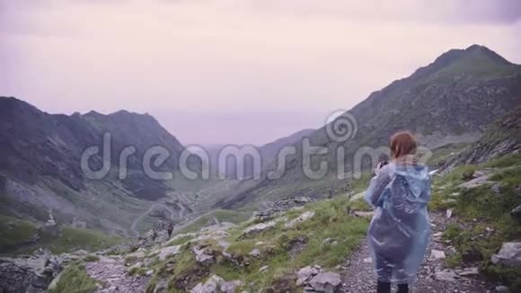 一位年轻的女徒步旅行者爬上山脉用相机拍摄风景罗马尼亚喀尔巴阡山脉视频的预览图
