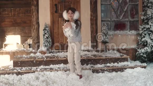 圣诞节或新年圣诞装饰品上一个孩子的肖像戴着毛耳机的小女孩把雪扔上来视频的预览图
