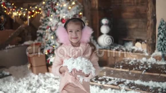 圣诞节或新年圣诞装饰品上一个孩子的肖像戴着毛耳机的小女孩把雪扔上来视频的预览图