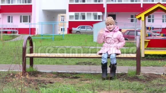 穿暖和衣服的快乐小女孩坐在长凳上视频的预览图