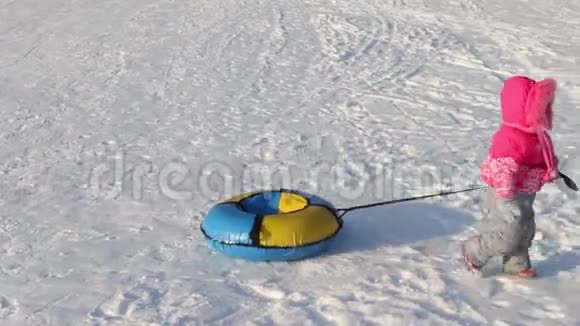 小女孩在雪地上拖着明亮的雪管视频的预览图