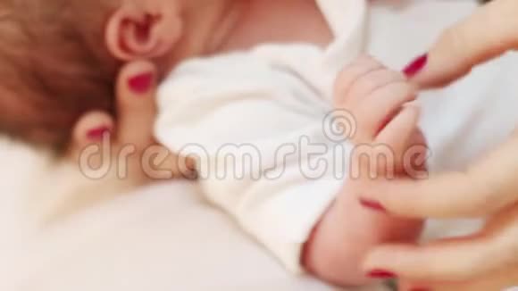 母亲的手抚摸着白色床上的小指特写视频的预览图
