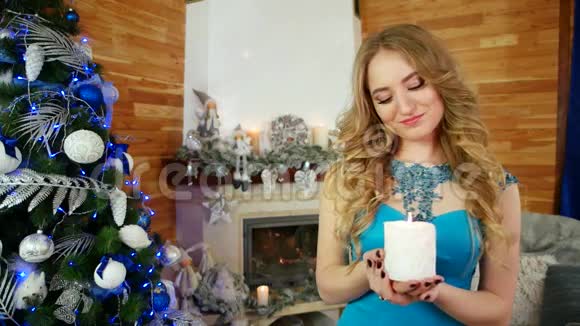 一个年轻女子手里拿着一支白蜡烛的肖像她在圣诞节附近举着一把圣诞火视频的预览图