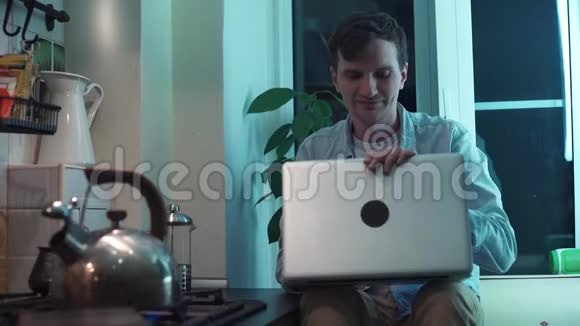 年轻人关上电脑坐在厨房里烧水壶烧炉子视频的预览图