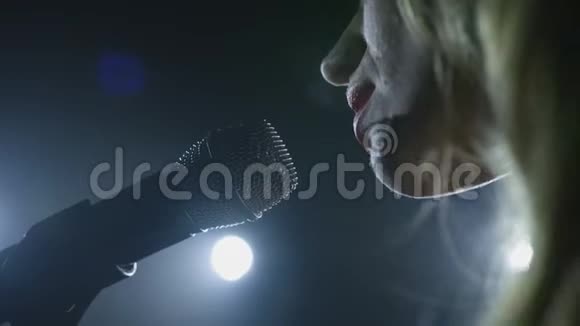 在黑色的烟雾背景上用麦克风特写歌手的脸歌手在舞台上唱一首歌视频的预览图