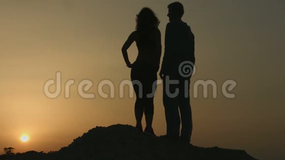男人在浪漫的约会中拥抱女人一对夫妇一起看美丽的日落视频的预览图