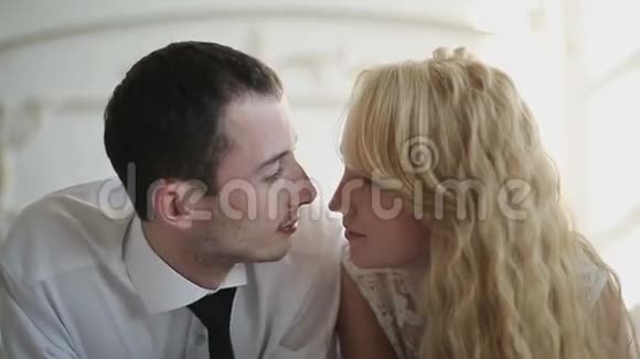 年轻夫妇在卧室的家里在床上亲吻和拥抱慢动作视频的预览图
