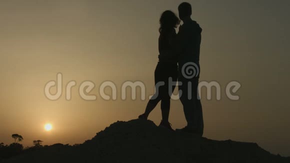快乐女孩亲吻男朋友情侣拥抱欣赏令人惊叹的日落美景视频的预览图