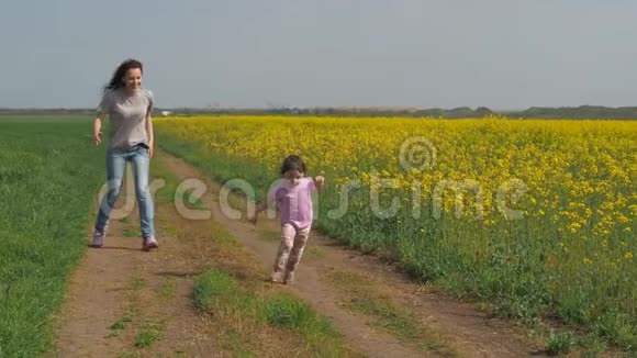 一个有孩子的女人在大自然中玩耍一个幸福的家庭正在新鲜的空气中奔跑一个带着孩子的女孩沿着一个乡村视频的预览图