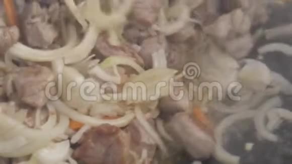 洋葱和大蒜是用肉炒在锅里的用蔬菜烹调炒肉慢动作视频的预览图