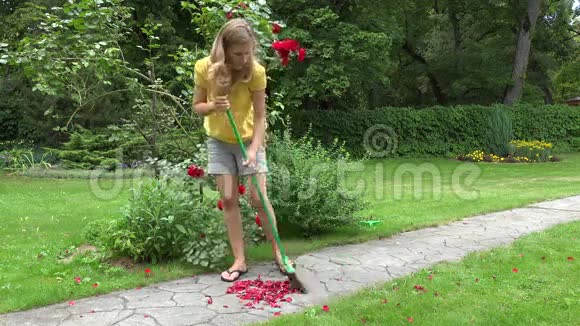 女人用扫帚扫着花园小径上落下的玫瑰花瓣4K视频的预览图