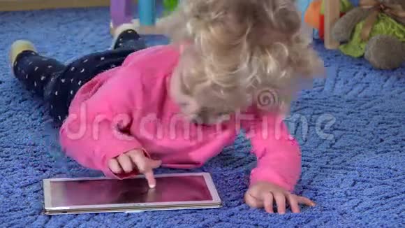 可爱的小女孩躺在肚子里用平板电脑视频的预览图