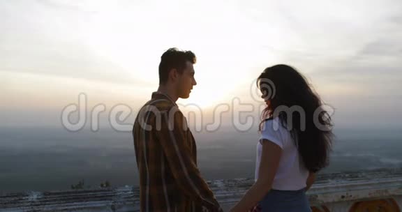 一对在山顶拥抱日出的情侣一对对相爱的游客视频的预览图