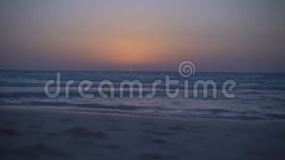 令人惊叹的神秘日落在海上晴朗的天空平静的大海带着小浪波浪在沙子上荡漾从视频的预览图
