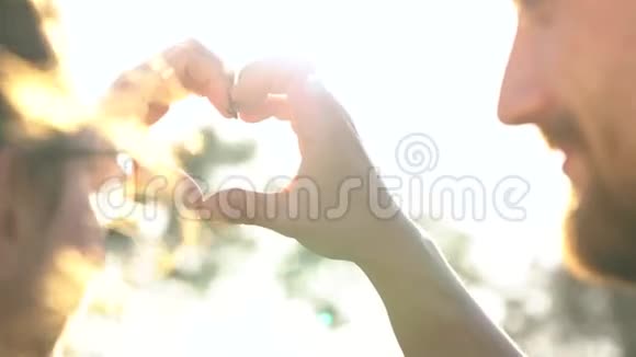 年轻一对相爱的情侣在日落时分用手做心的象征视频的预览图