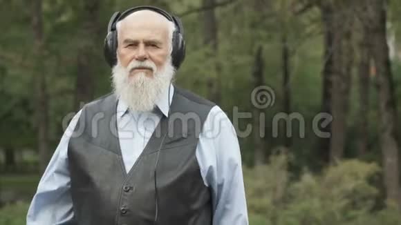 白发男子用耳机听音乐的肖像视频的预览图