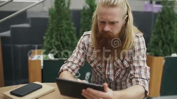 带着平板电脑的年轻人坐在户外的咖啡馆里放松休息视频的预览图