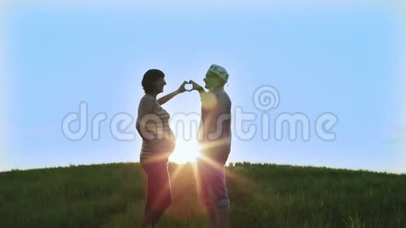 一对相爱的夫妇在蓝天和明亮的太阳的背景下做着手指的心视频的预览图