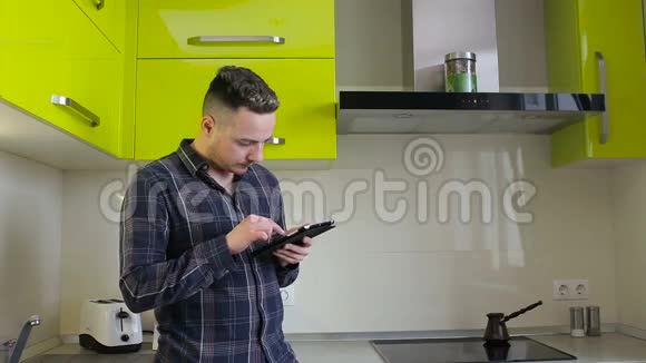 男人在平板电脑上看新闻在厨房里喝咖啡视频的预览图