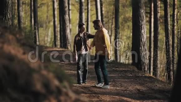 一个男人在树林里吵架时抓住他留胡子的朋友的肩膀视频的预览图