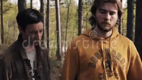 男人在森林里争吵时抓住他蓄着胡须的朋友的肩膀视频的预览图
