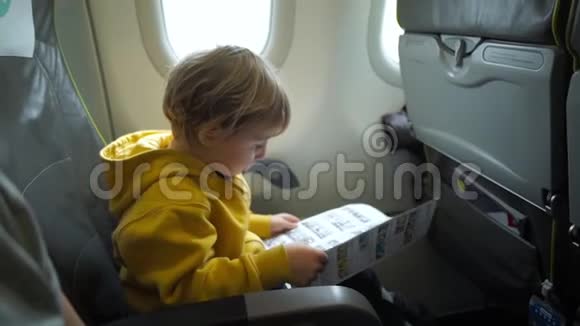 飞机上一个穿黄色夹克的男孩在读安全说明书时慢镜头视频的预览图