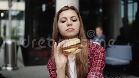 一位年轻有魅力的女士在城市街头咖啡馆吃汉堡视频的预览图