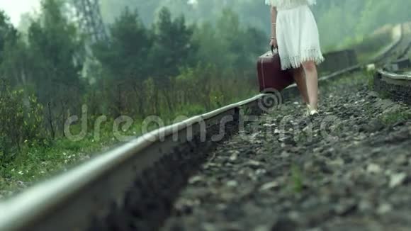 带着手提箱在铁轨上行走的女孩视频的预览图