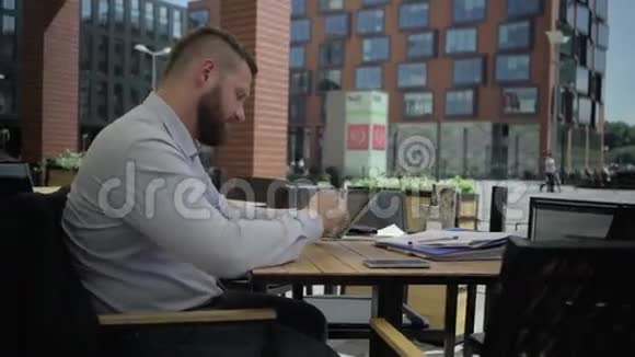 疲惫的商人在咖啡馆里浏览平板电脑视频的预览图