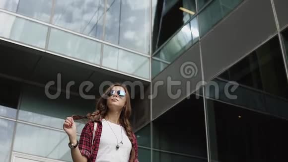梦想中的女孩戴着太阳镜站在现代建筑附近视频的预览图