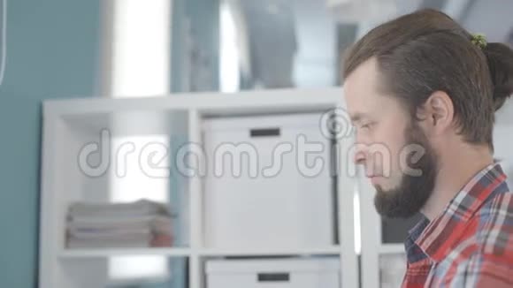 一个留着胡子头上有一簇头发的人在办公室工作视频的预览图