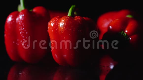 成熟的红辣椒在黑色背景上旋转特写慢动作一滴水从物体上流下来视频的预览图