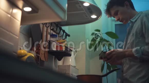 男人在厨房的炉子上用锅做饭用平板电脑视频的预览图