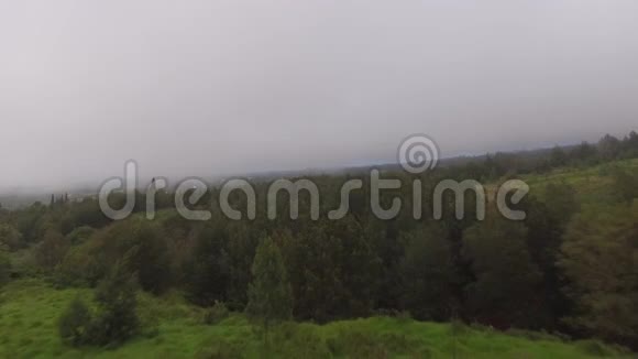 4k空中无人机照相机在夏日雾雾霭灰雨云中看到绿油油的大郊野山地视频的预览图