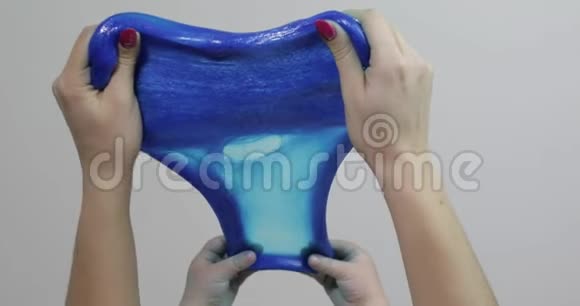 女人和孩子的手玩着令人满意的蓝色黏液粘稠物质抗压力视频的预览图