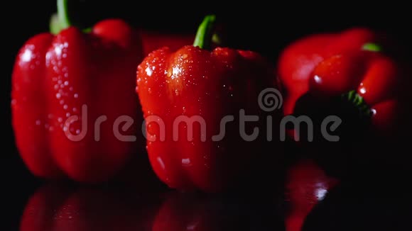 成熟的红辣椒在黑色背景上旋转特写慢动作一滴水从物体上流下来视频的预览图