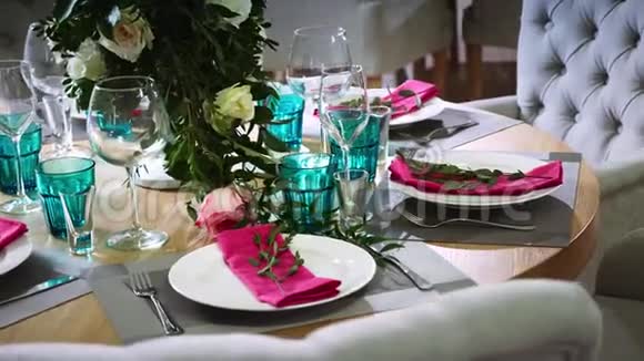 一张圆形的木制桌子上面装饰着由白色盘子和粉色餐巾纸做成的花饰视频的预览图