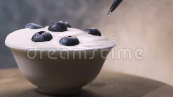 用勺子吃蓝莓和奶油或酸奶水果背景视频的预览图