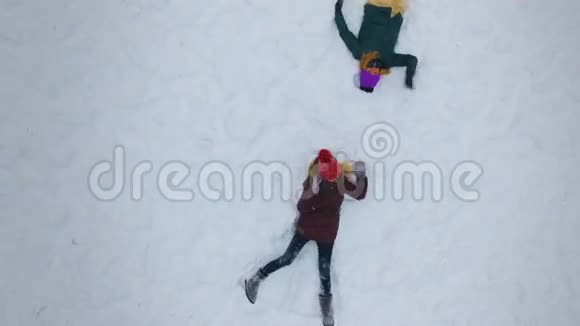 年轻女孩在阳光明媚的冬日做雪天使慢动作4K视频的预览图